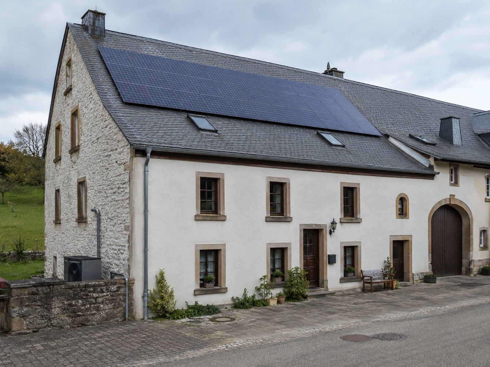 Ancienne ferme luxembourgeoise en pierre dont le toit porte des panneaux photovoltaïques
