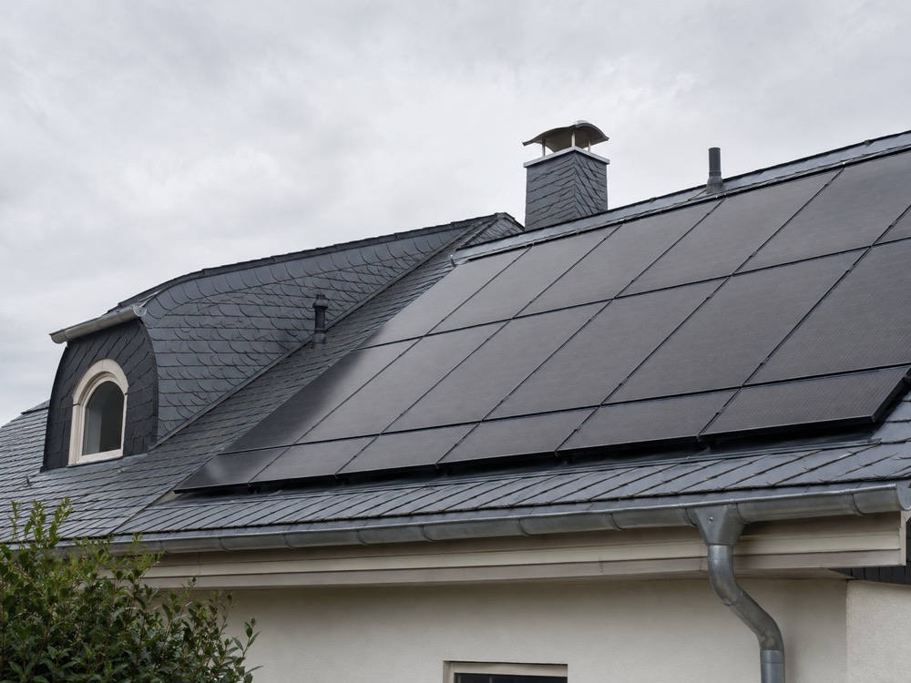 Toiture en ardoise mansardée entièrement couverte de panneaux photovoltaïques noirs